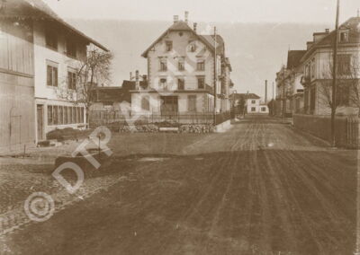 Postkarte aus der Reihe «Anno dazumal» - Die Poststrasse Uster mit Blick zum Bahnhof, 1904/05. Im Mittelgrund vorne Poststrasse 12 (das ehemalige Schuhgeschäft Dosenbach), rechts Poststrasse 11.