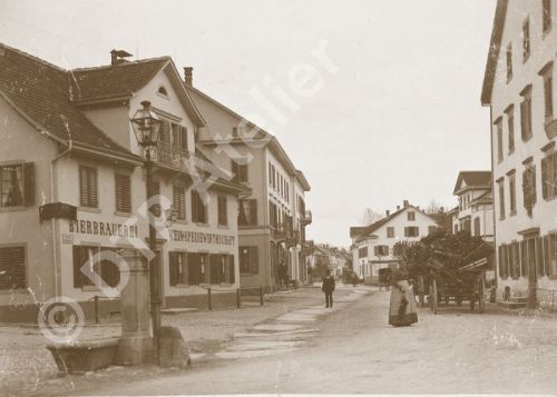 Postkarte aus der Reihe «Anno dazumal» - Blick vom Sternenplatz mit Dorfbrunnen und Laterne (heutiger Sternenkreisel) in die Florastrasse, Uster, Winter 1892